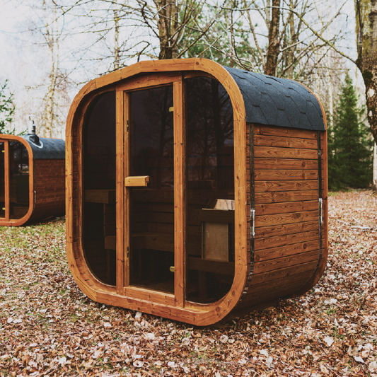 Wooden pod structure sauna in a natural setting with trees and fallen leaves.