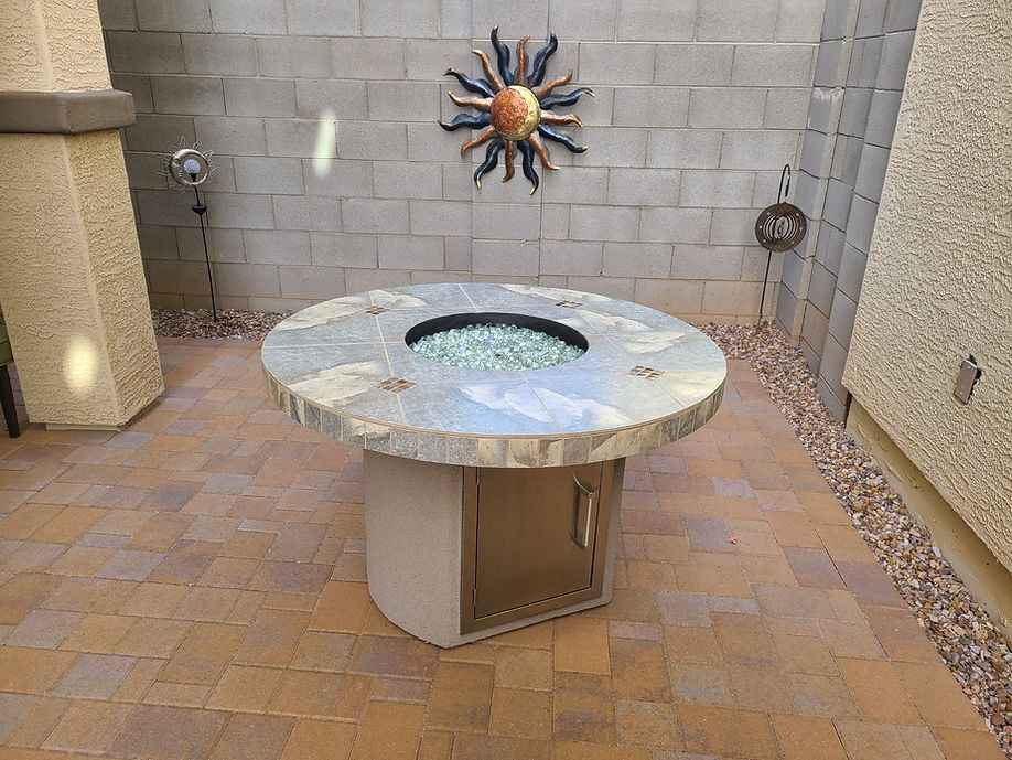 Round stone fire pit table with decorative elements on a patio