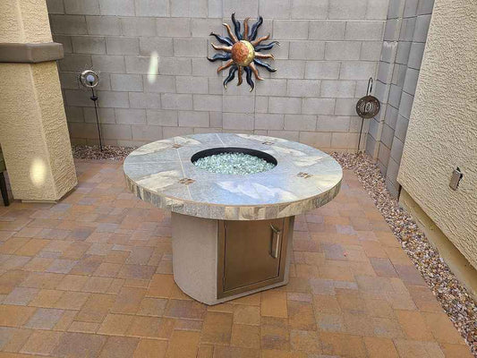 Round stone fire pit table with decorative elements on a patio