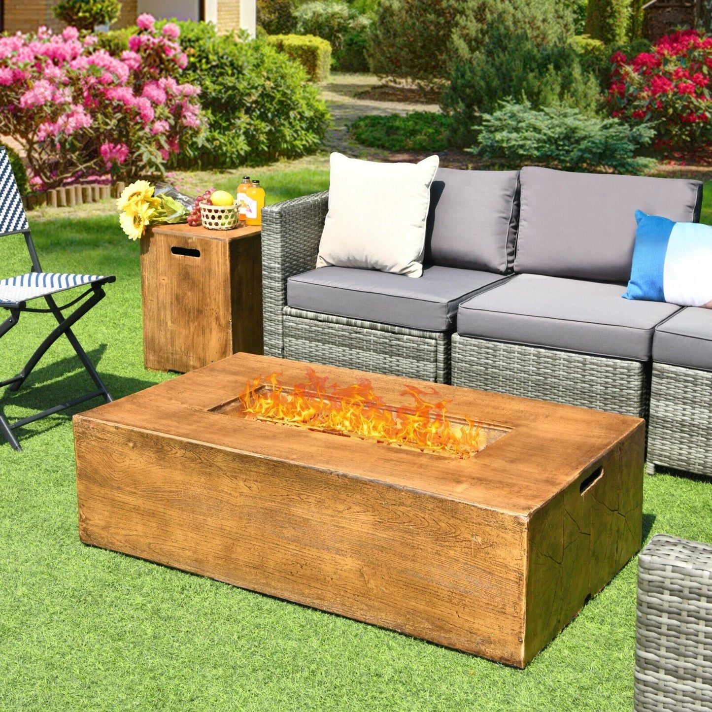 Outdoor patio setting with a fire pit table, sofa, and chairs in a garden.