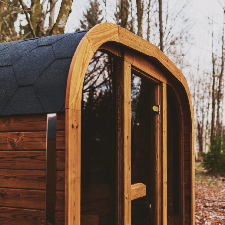 Wooden sauna with a dark roof in a forest setting